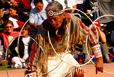 Man performs Native American Pow-wow dance for audience.