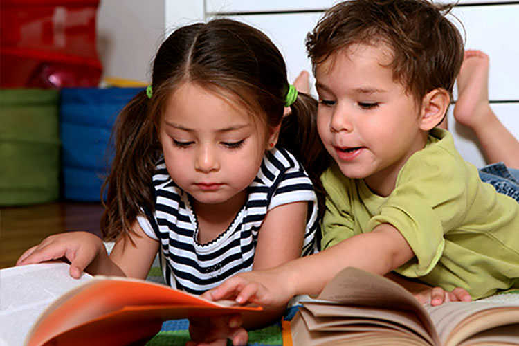 Pre-school children help each other learn to read.